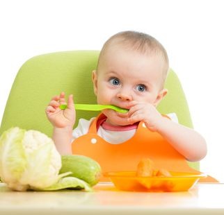 happy baby girl eating vegetables