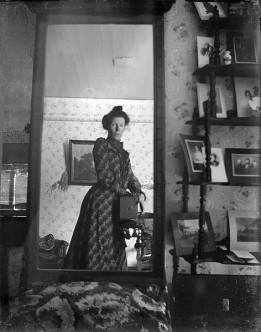 Unidentified_woman_taking_her_own_photograph_using_a_mirror_and_a_box_camera,_roughly_1900