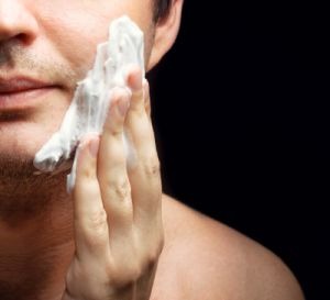 Young man applying a shaving foam. Skin protection.