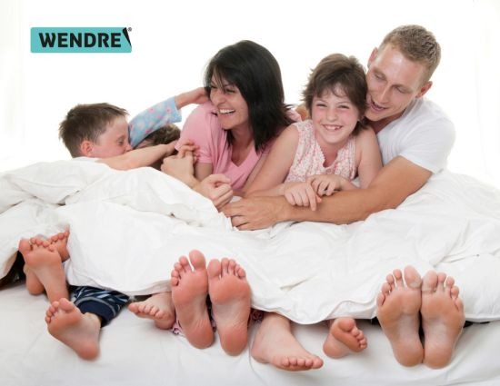 A family and their feet in bed under a duvet.