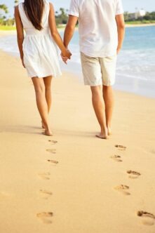 Couple holding hands walking on beach on vacation