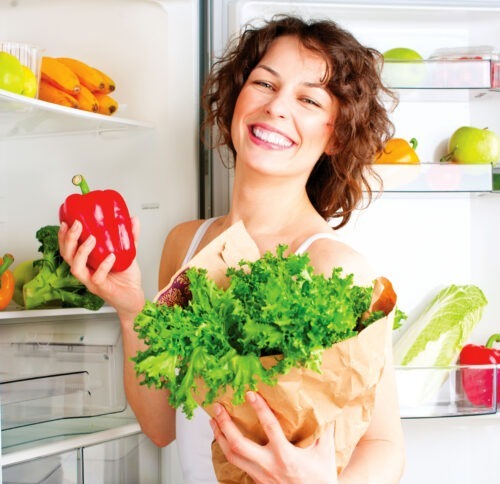 Beautiful young woman near the refrigerator with healthy food