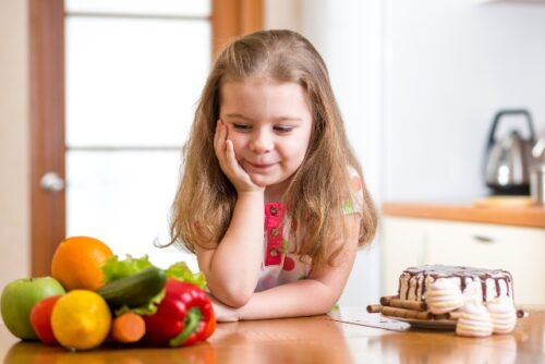 child choosing between healthy vegetables and tasty sweets