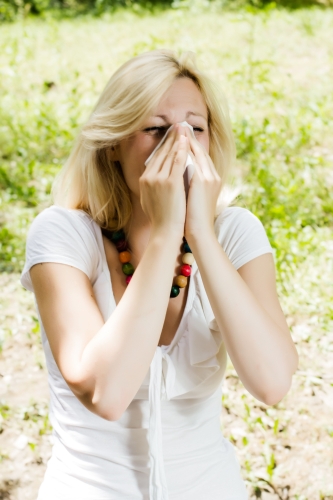 Young woman blowing nose outdoor, pollen allergy,