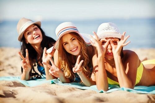 summer holidays and vacation - girls sunbathing on the beach