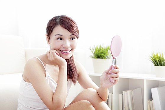 Woman caring of her beautiful skin and face by mirror at home, asian beauty