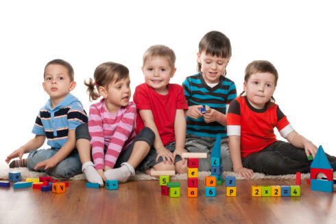 Five children are playing on the floor in the kindergarten