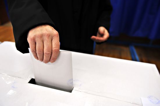 Close-up of a man's hand putting his vote in the ballot box