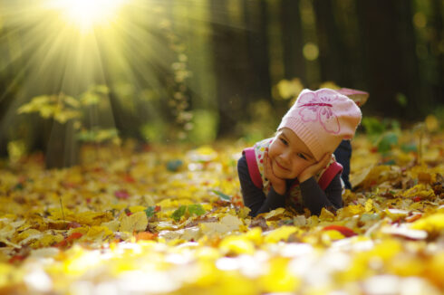 Little girl in the autumn forest on a sunny day