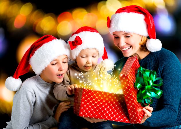 Mother with children opens the box with gifts on the christmas holiday - indoors