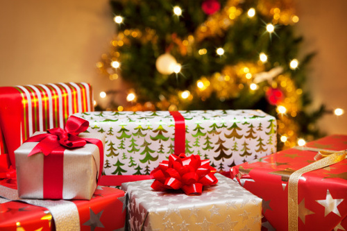 Group of Christmas gifts in front of tree.