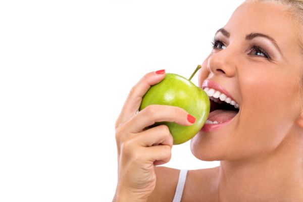 woman eat green apple, biting apple with perfect teeth
