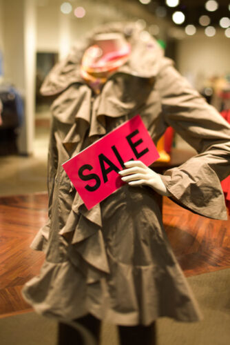 Mannequin holding sale sign in retail mall store.