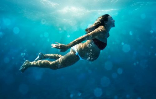 Underwater view of pregnant woman swimming --- Image by © Ben Welsh/Corbis