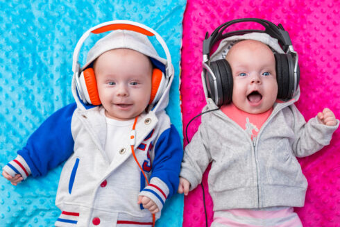 Happy twin babies listening to the music on headphones