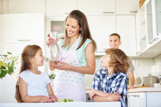 Mutter und Kinder mit einer Karaffe in der Küche