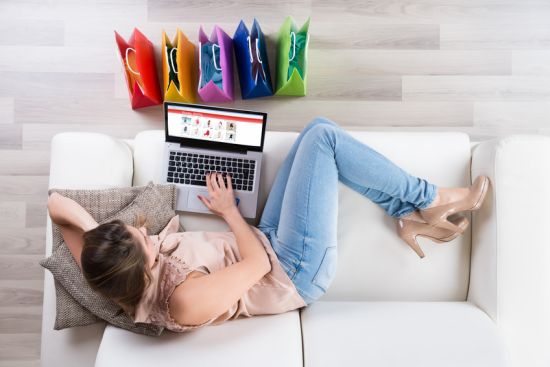 Young Woman On Sofa Shopping Online With Laptop