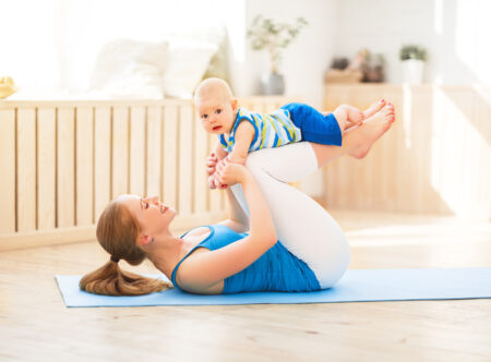 sports mother is engaged in fitness and yoga with a baby at home