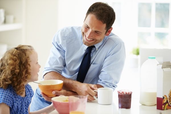 Father And Daughter Having Breakfast In Kitchen Together