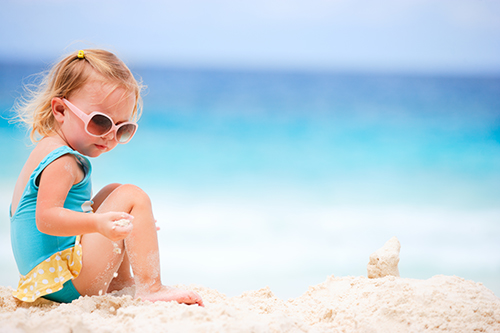 Adorable toddler girl playing on white sand beach