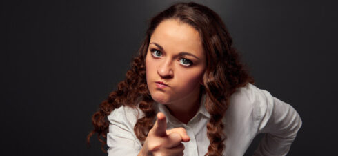 studio shot of angry woman pointing at camera. picture over dark background