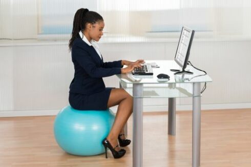 Young African Businesswoman Sitting On Fitness Ball Using Computer In Office