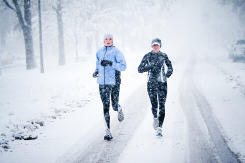 Kara Roy (black jacket) and Jennifer Lee (blue jacket) run down Mountain Avenue in a snowstorm.