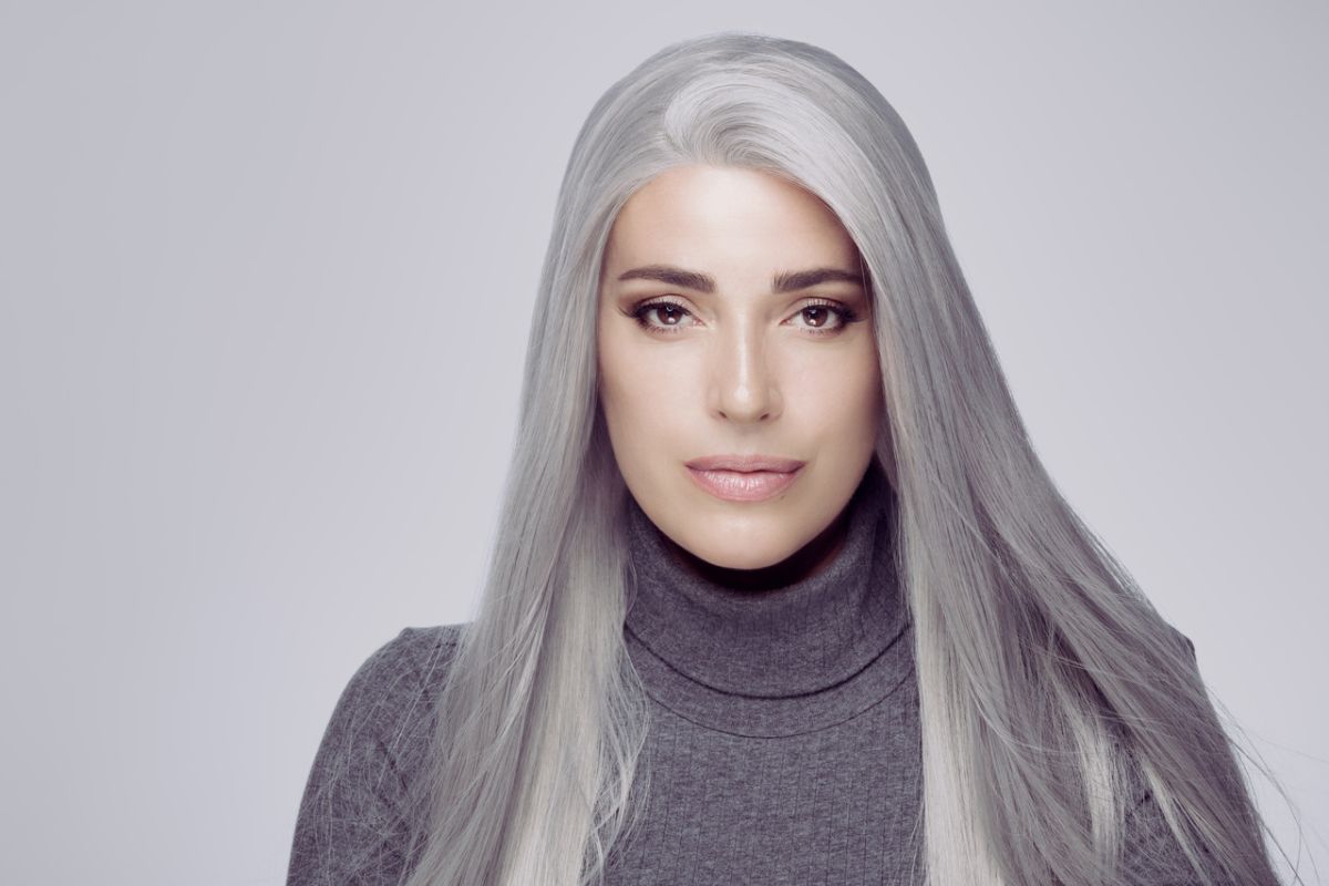 Dorosła kobieta z długimi, siwymi włosami i w szarym swetrze