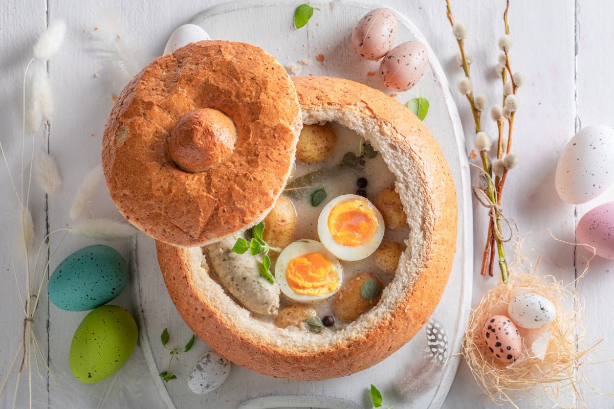 Tradycyjne potrawy wielkanocne na wielkanocnym stole – żurek wielkanocny i barszcz biały z majerankiem, czosnkiem i liśćmi laurowymi